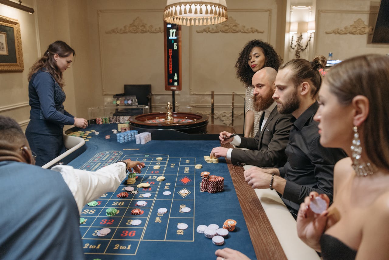 Diverse group enjoying a night of gambling at a luxurious casino roulette table.